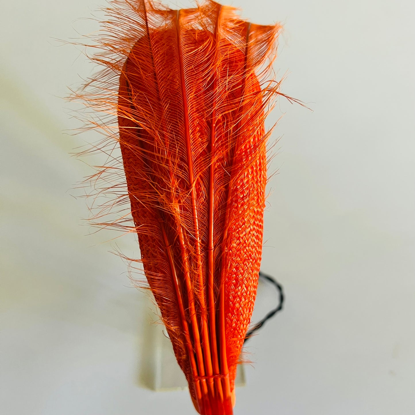 An orange straw padded headband finished with delicate feather trim