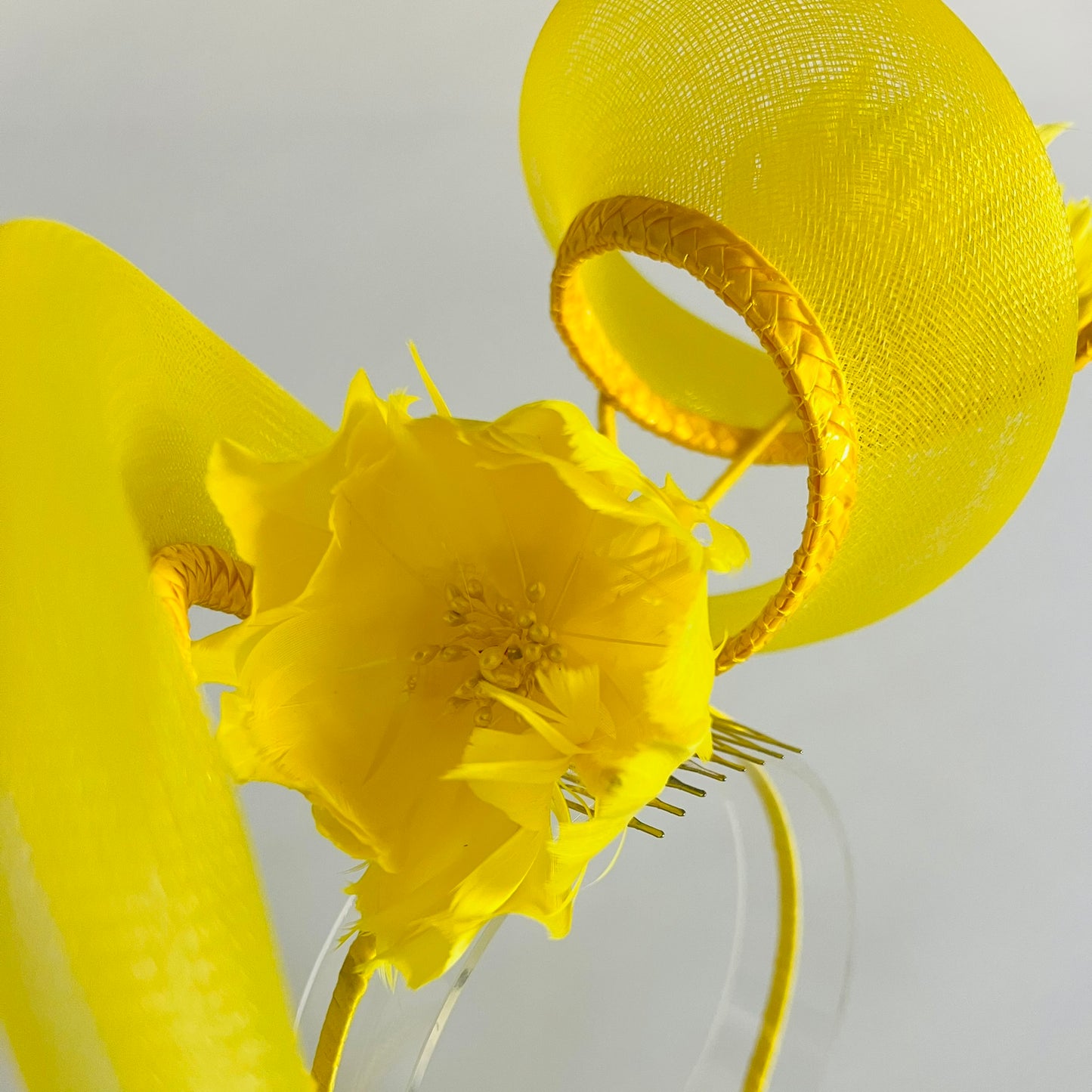 A vibrant headband featuring a swirl of crinoline and handmade feather flowers, all in bright yellow for a striking finish.
