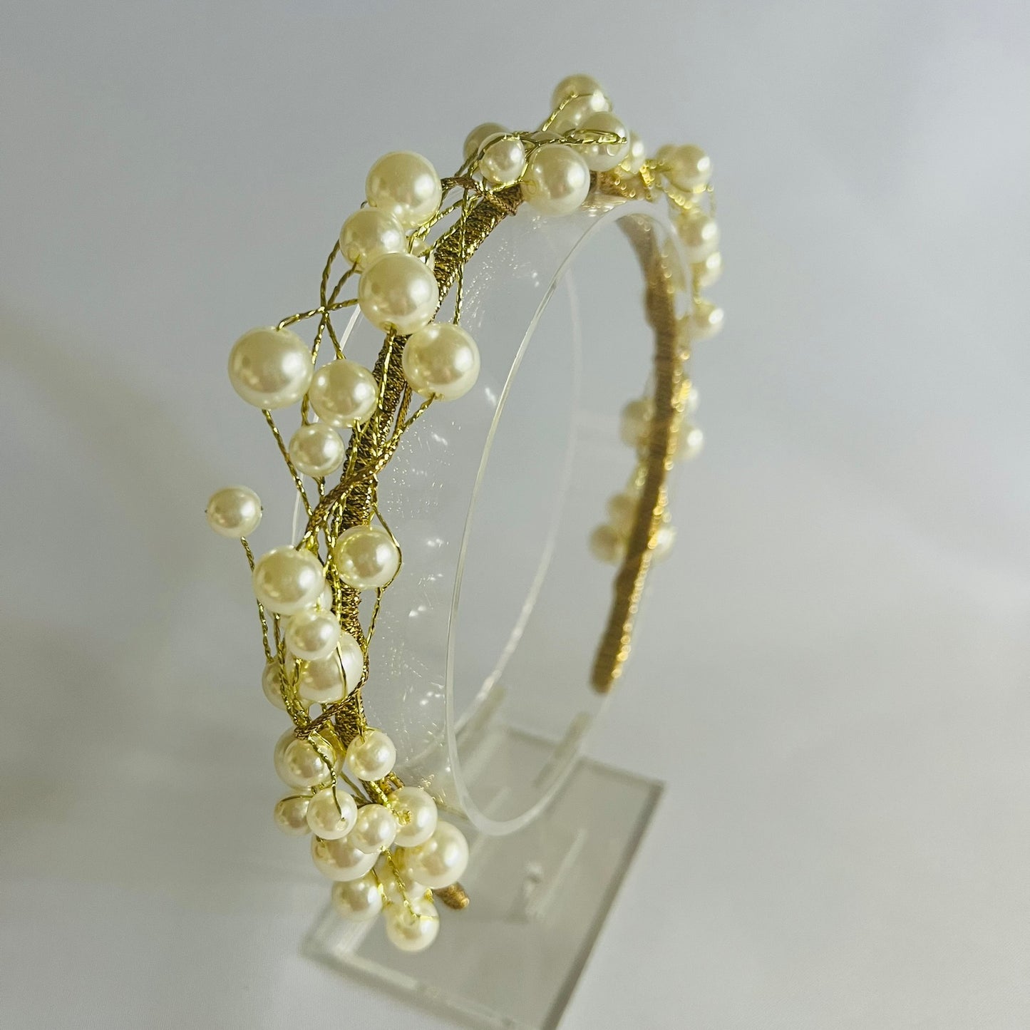 A chic headband adorned with clusters of pearl beads and touches of gold, creating a timeless and elegant look.