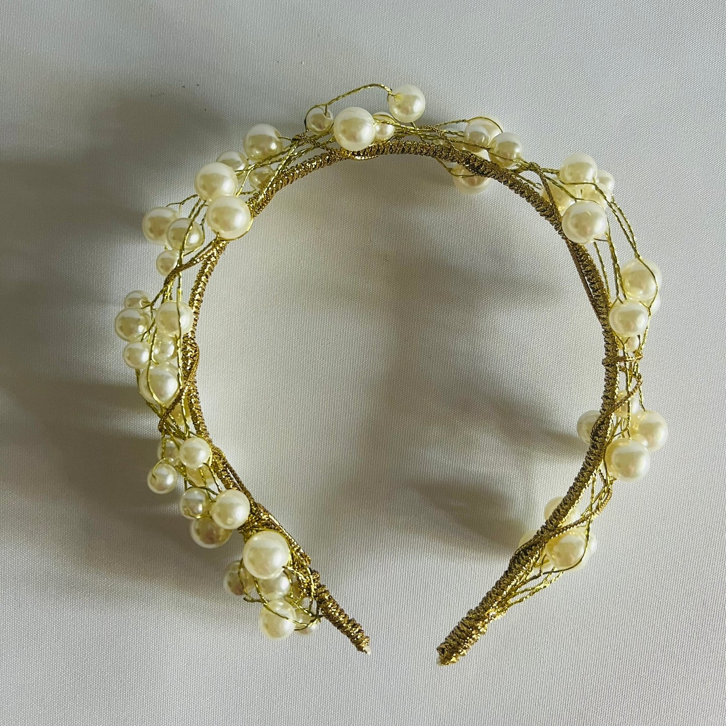 A chic headband adorned with clusters of pearl beads and touches of gold, creating a timeless and elegant look.