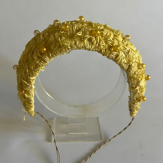 A buttercup yellow padded headband. Made with textured straw and finished with delicate bead trim.