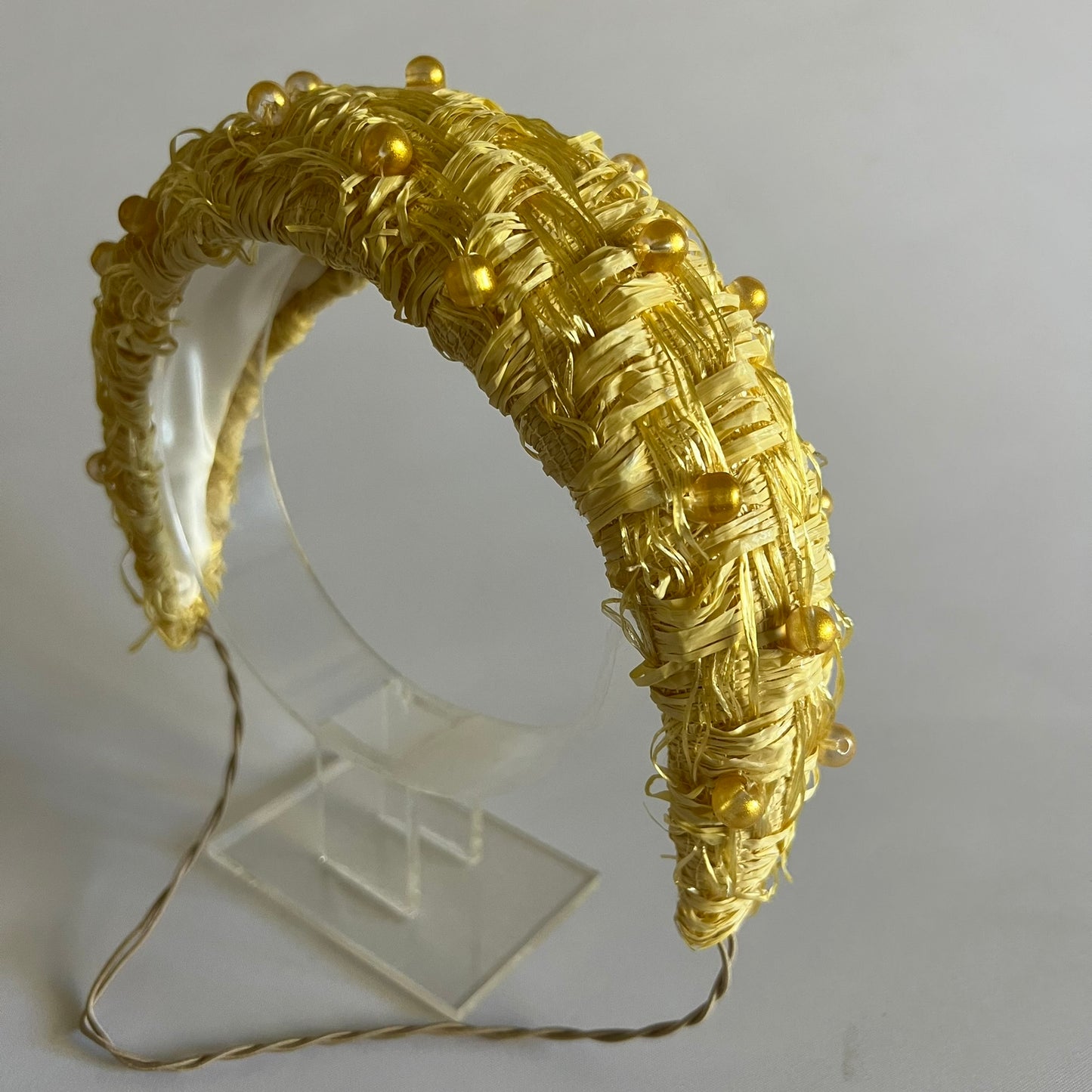 A buttercup yellow padded headband. Made with textured straw and finished with delicate bead trim.