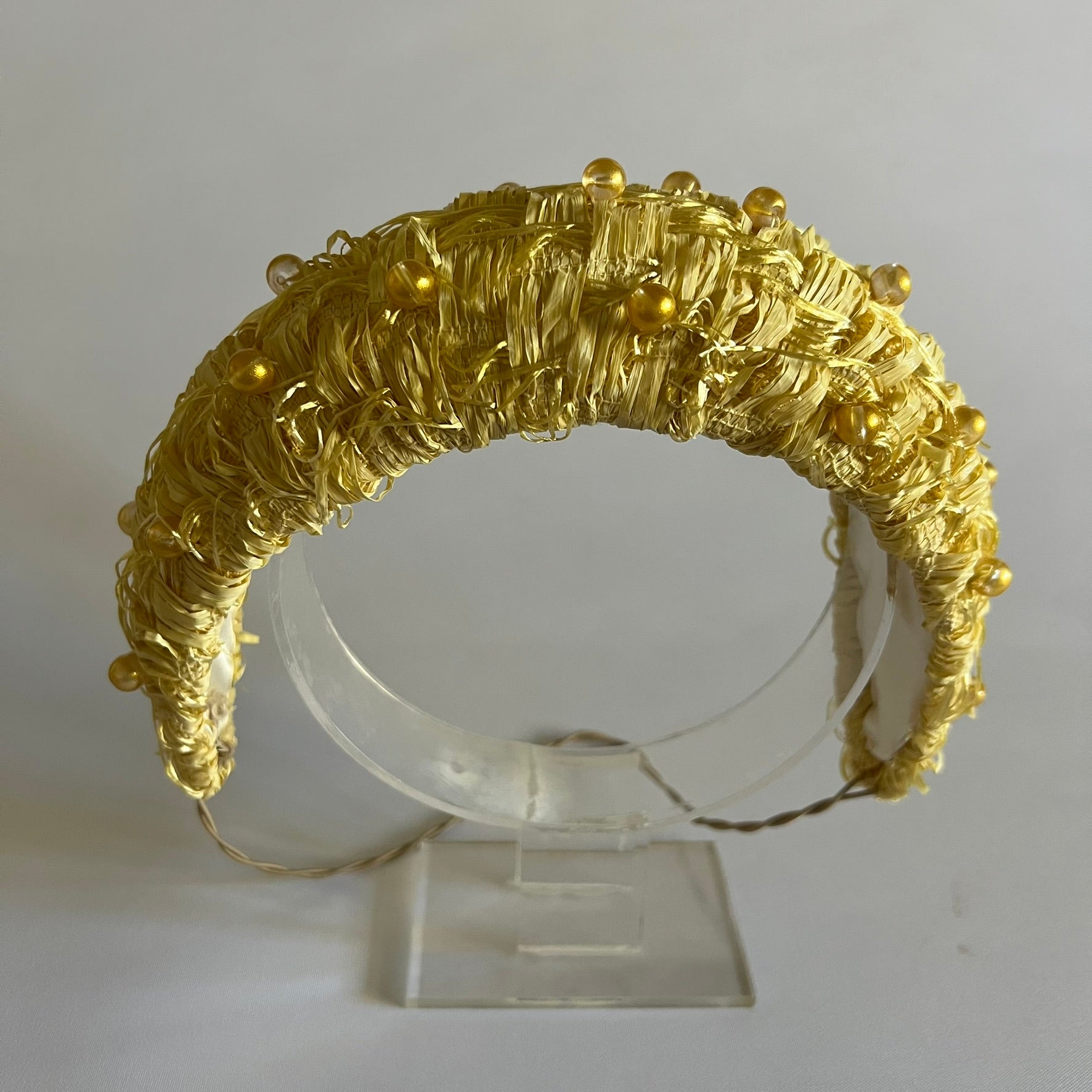 A buttercup yellow padded headband. Made with textured straw and finished with delicate bead trim.