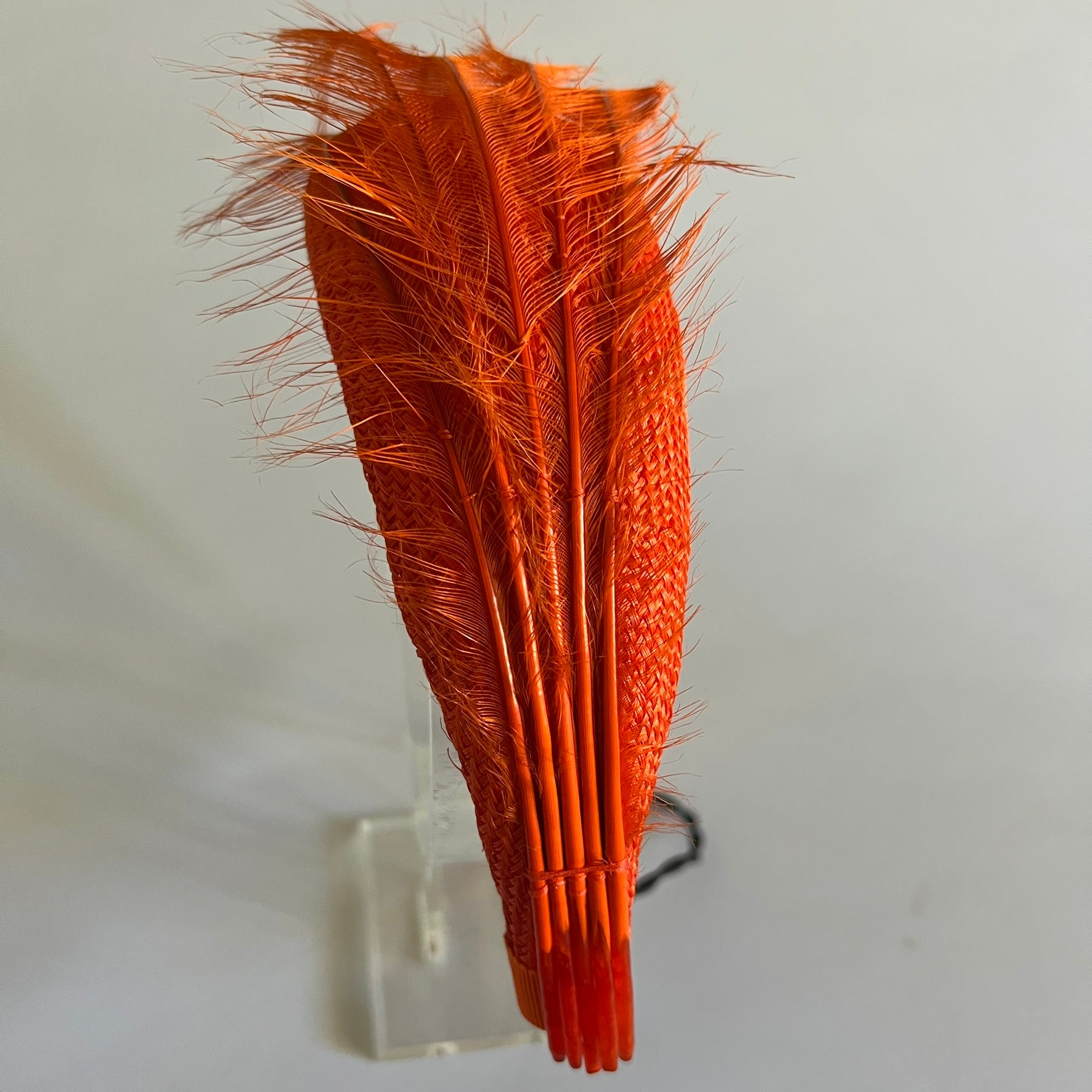  An orange straw padded headband finished with delicate feather trim