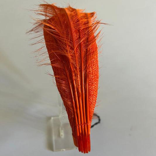  An orange straw padded headband finished with delicate feather trim