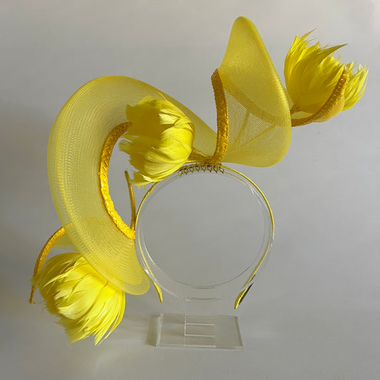 A vibrant headband featuring a swirl of crinoline and handmade feather flowers, all in bright yellow for a striking finish.