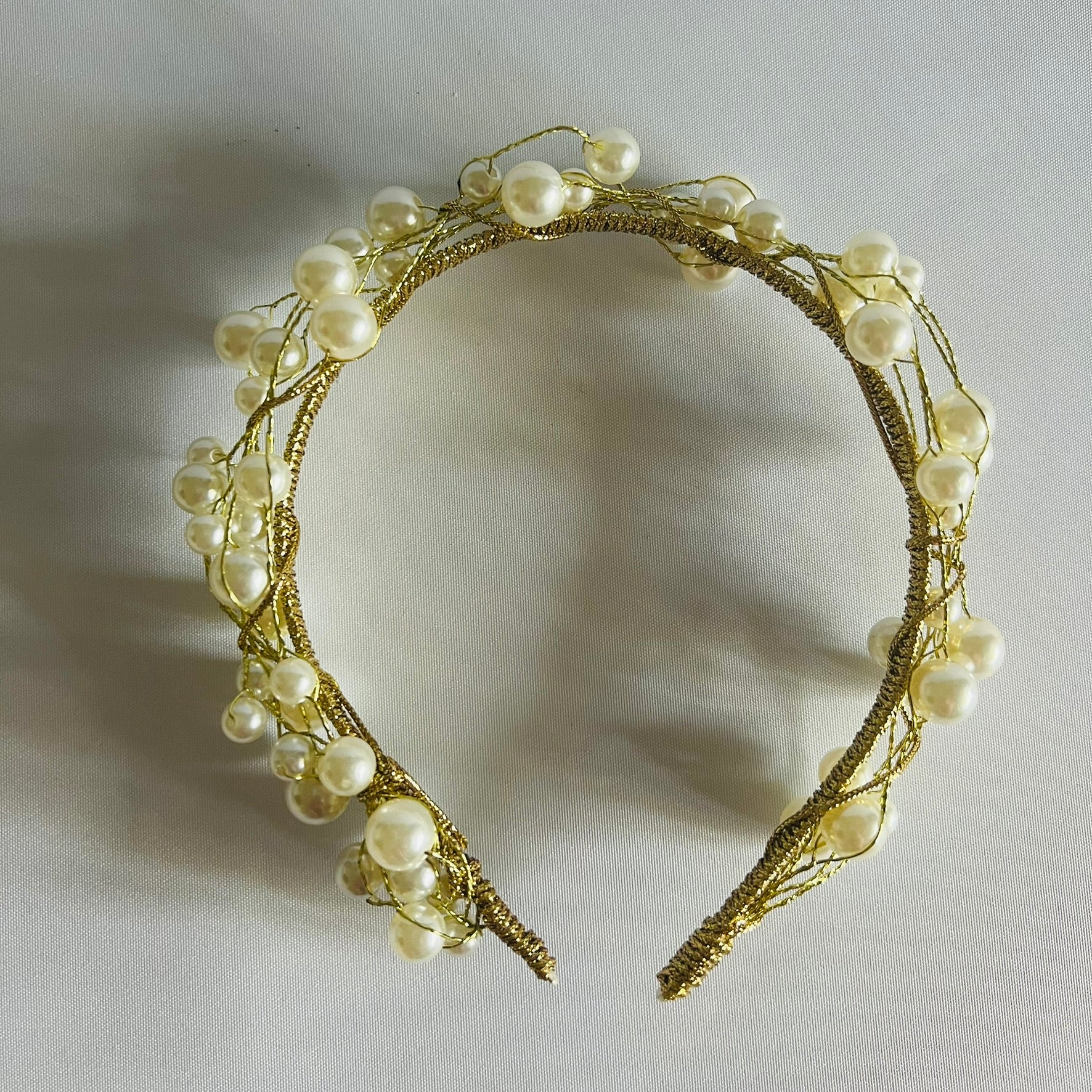 A chic headband adorned with clusters of pearl beads and touches of gold, creating a timeless and elegant look.